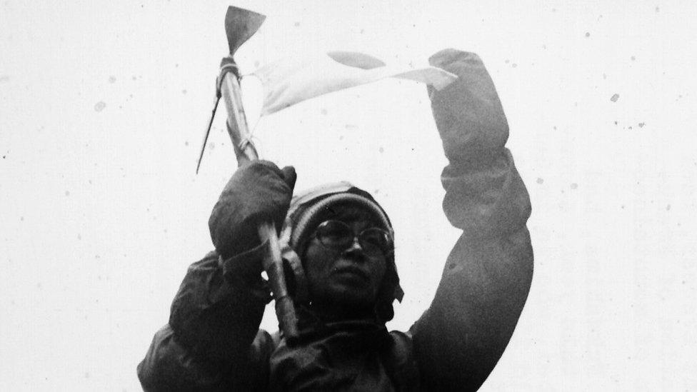 Portrait of Japanese mountaineer Junko Tabei giving a climbing demonstration next to a rubble pile, outside Frankfurt Station, circa 1975