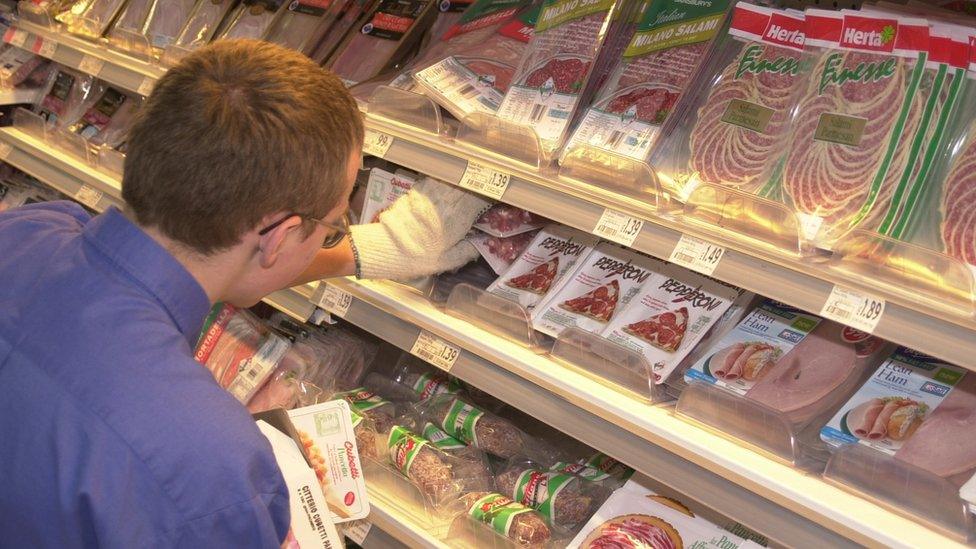 Staff member stacking shelves in a Sainsbury's store