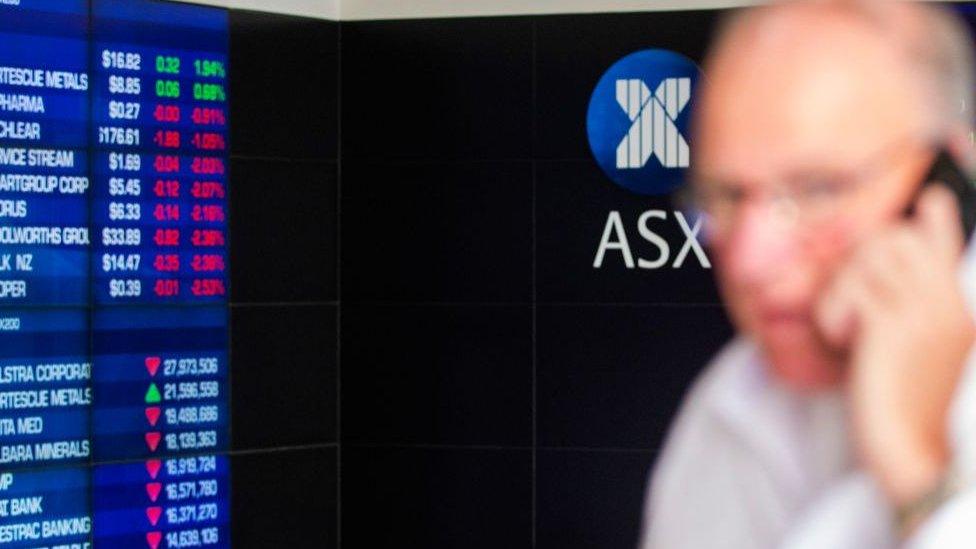 Man in front of ASX market board.