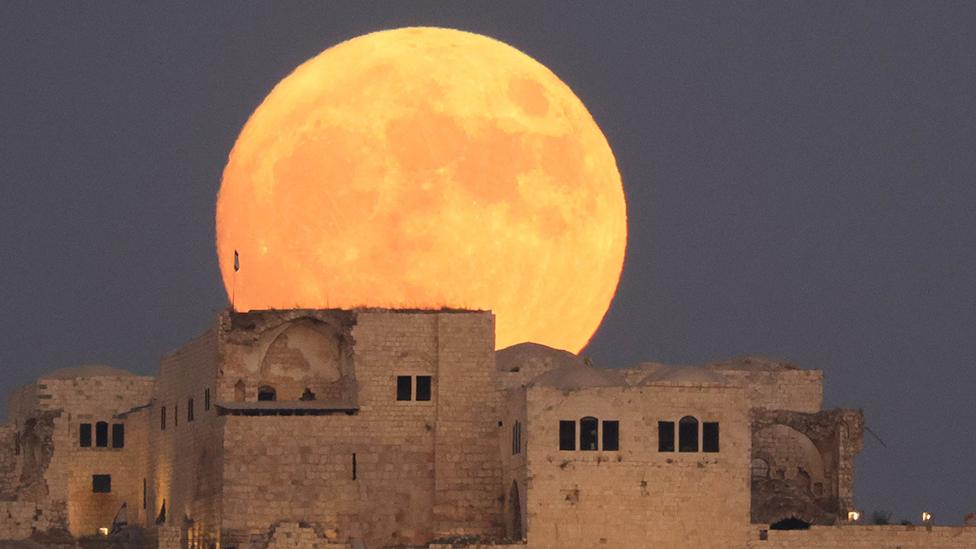 Moon rising over buildings