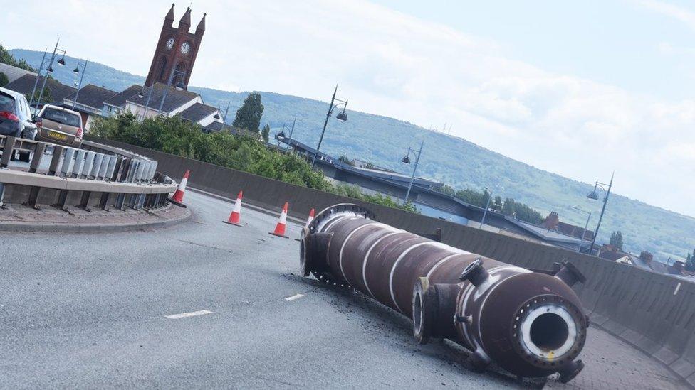 A large metal pipe lies on the road