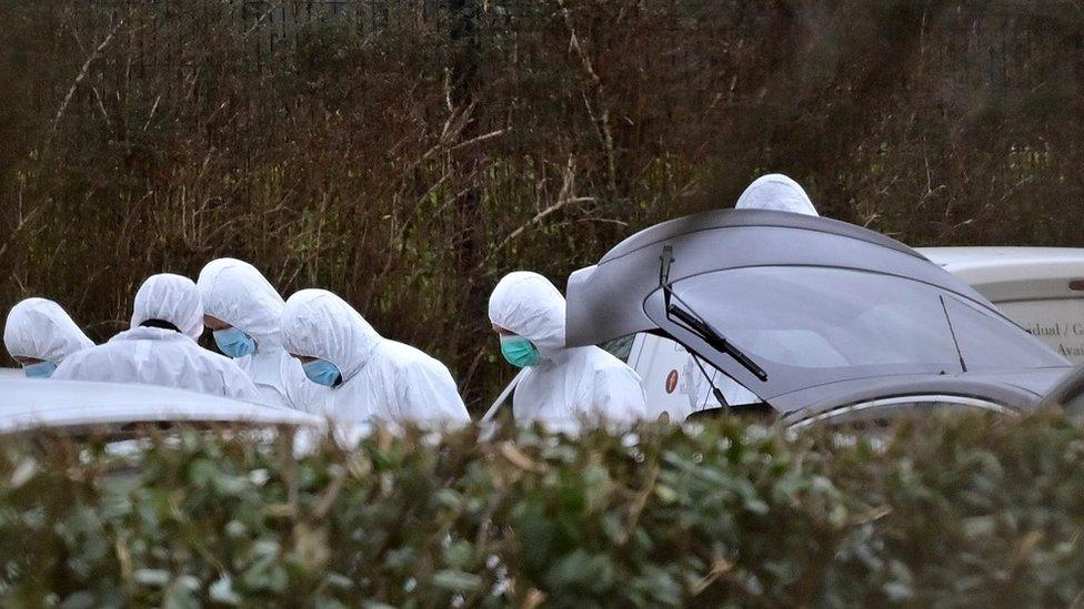 Forensics officers examine vehicles at the sports complex where the shooting occurred