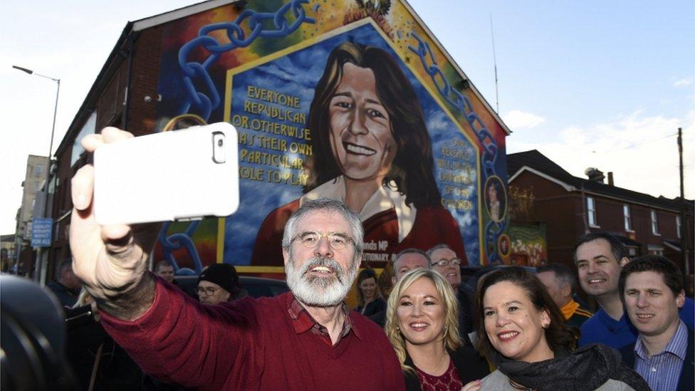 Sinn Féin President Gerry Adams takes a selfie with Sinn Fein northern leader Michelle O'Neill and party officials after they speak to media outside the Sinn Fein offices on the Falls Road in Belfast after the March 2017 election