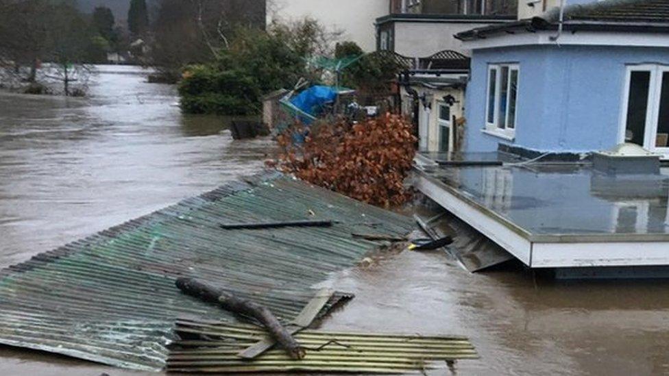 Flood water, carrying debris such as corrugated iron sheets and wooden pallets, up to the second floor of a house