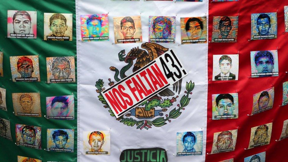 A Mexican flag and some pictures of the 43 missing students is seen in a march to demand justice for the missing students