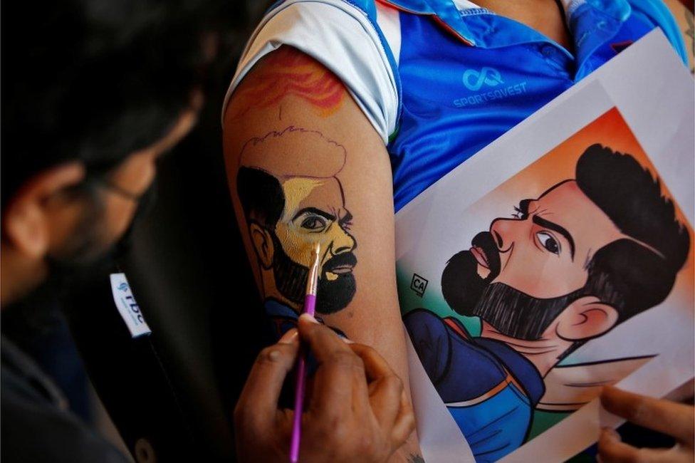 A cricket fan gets an arm painted with the image of India"s cricket captain Virat Kohli before the start of the first match between India and Pakistan in Twenty20 World Cup Super 12 stage in Dubai, in Ahmedabad, India, October 24, 2021.