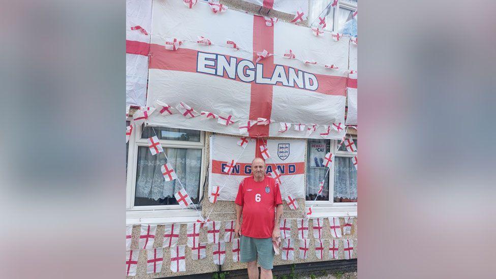 Paul Bibby standing in front of his house covered in England flags