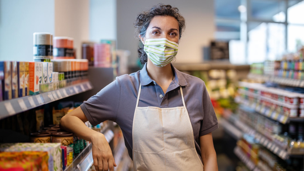 A shop assistant in a shop wearing a mask