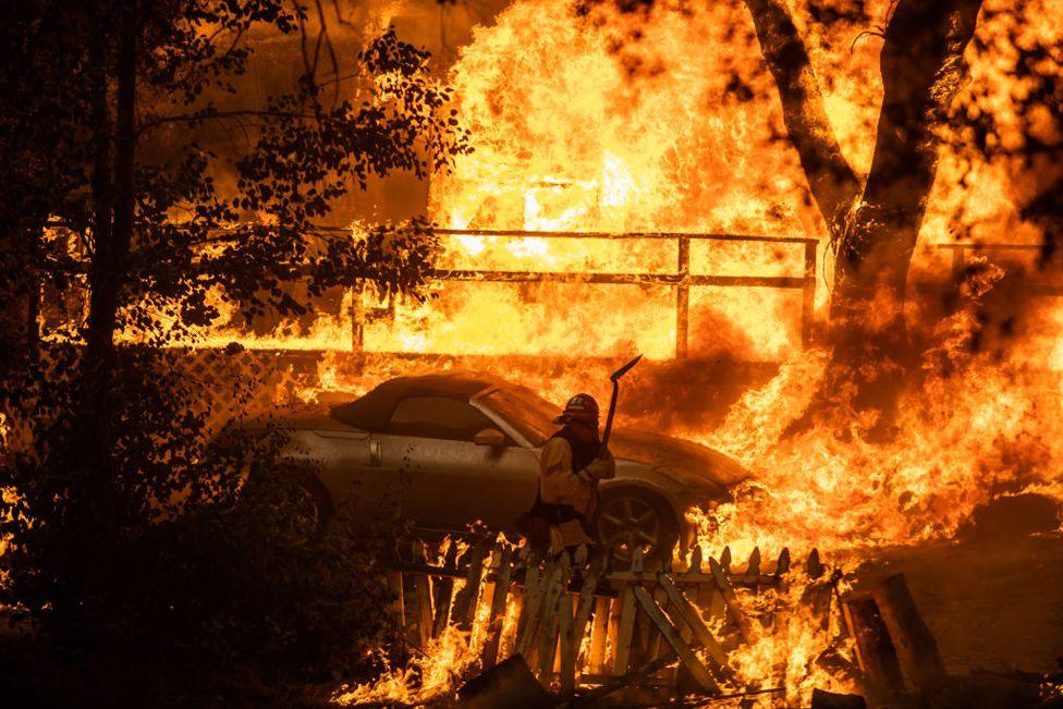 A Firefighter walks in a evacuated home in flames at El Cariso Village as the Airport Fire burns on September 10, 2024 in Lake Elsinore, California.