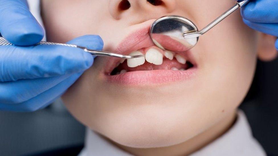 A dentist checking a child's teeth