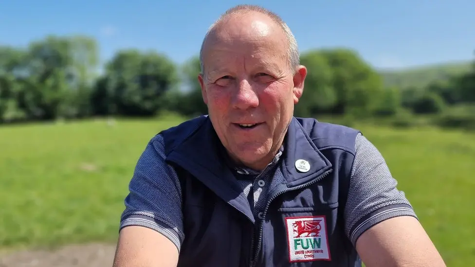 Ian Rickman, president of the Farmers' Union of Wales (FUW), wearing a polo shirt and a gilet, standing in a field smiling at the camera.