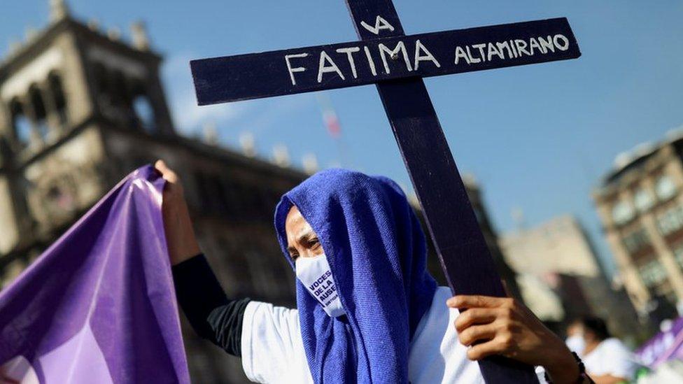 A woman holds a cross as relatives and friends of victims of femicide take part in a march in Mexico City