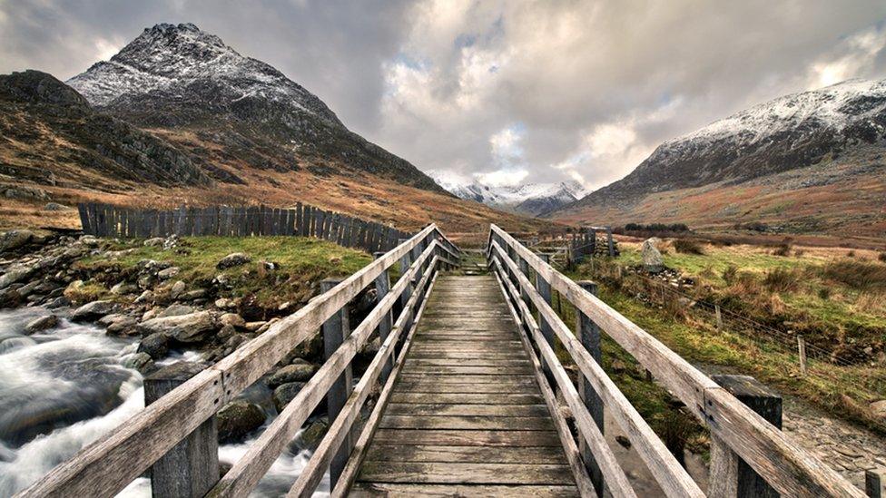 This view of a bridge over Nant Gwern y Gof river with Tryfan mountain in the distance.