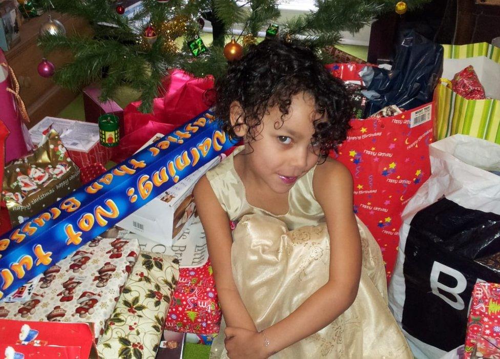 Giorgia Green in front of Christmas tree surrounded by presents and wrapping paper