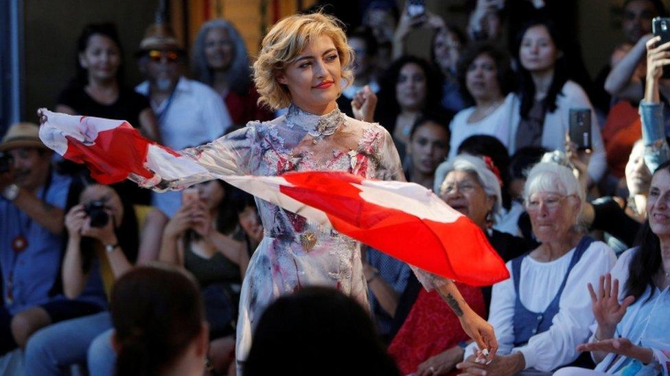 Willow Riley rips a Canadian flag while modelling clothes from designer Oka during the inaugural Vancouver Indigenous Fashion Week in Vancouver, British Columbia, Canada July 27, 2017.