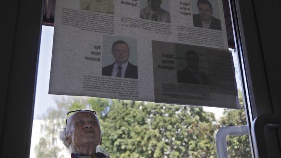 A woman reads official leaflets with biographical details of competing parliamentary candidates in Minsk (11 September 2016)