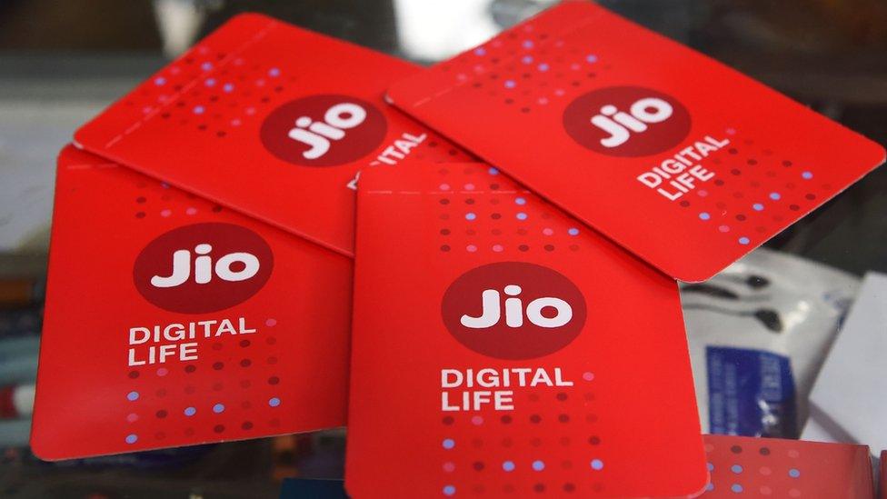 A shopkeeper displays JIO simcards at a mobile phone store in Mumbai on July 19, 2017.