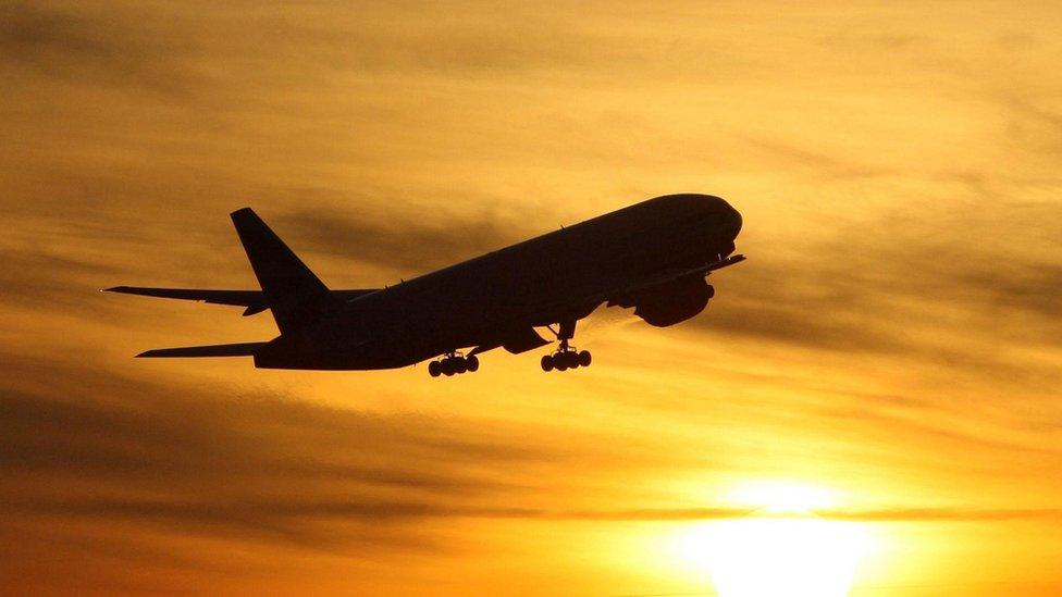 Plane flying against sunset backdrop