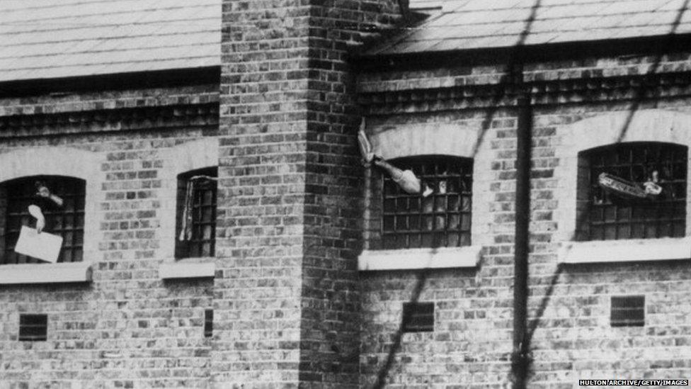 Imprisoned suffragettes waving through the barred windows of Holloway Prison, London