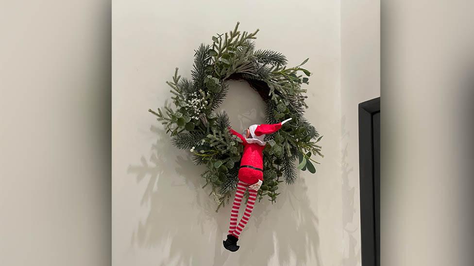 An elf climbing up a wreath