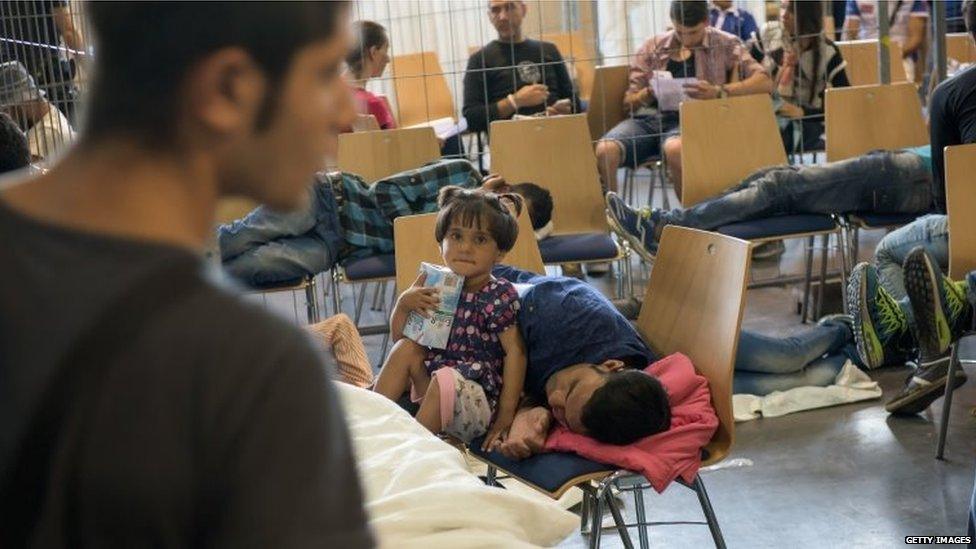 Refugees who arrived in Germany by crossing the nearby Austrian border wait in the waiting zone at the X-Point Halle initial registration centre of the German federal police (Bundespolizei) on July 15, 2015