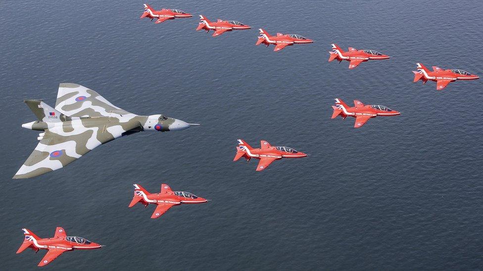 Vulcan bomber flying in between the Red Arrows