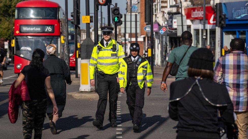 Police officers patrol through Stamford Hill, an area of London with a large Jewish community, on 10 October