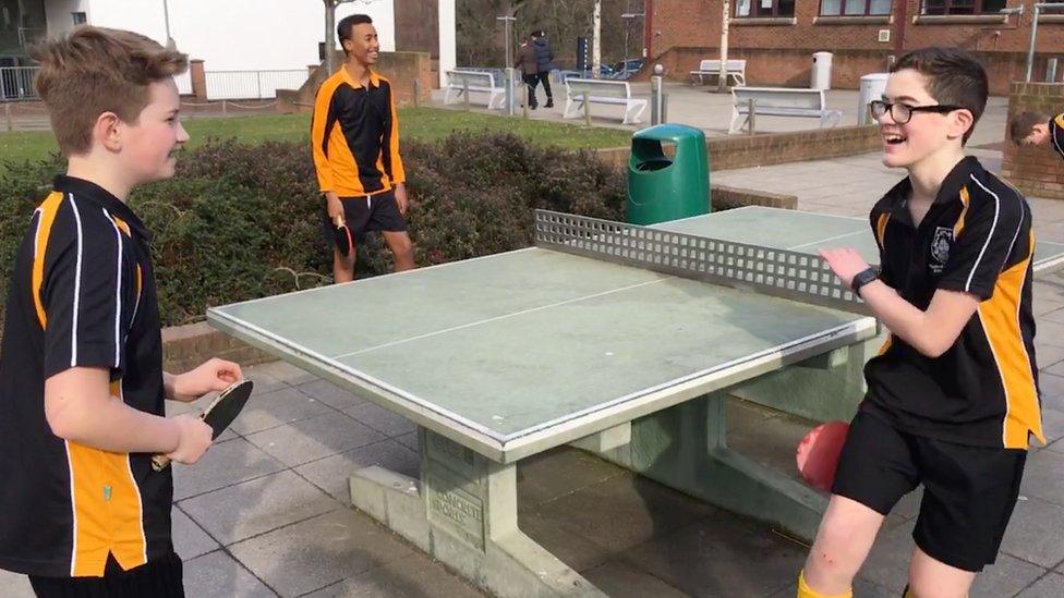 T-shirt boys playing table tennis outside in February