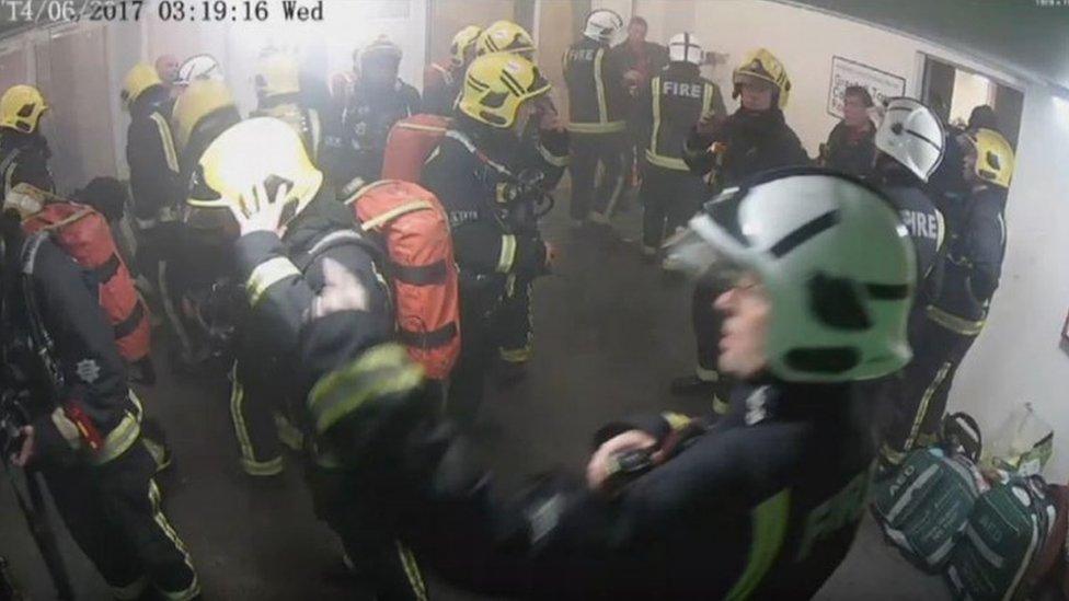 Glynn Williams (top right) pointing at a wall on the ground floor of Grenfell Tower on 14 June 2018