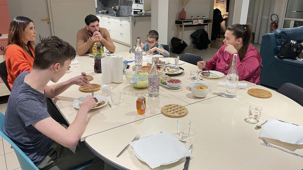 French orphans sit around a table eating together