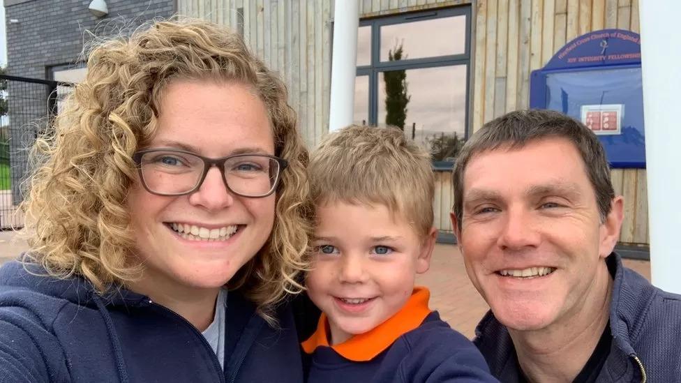 Isaac smiling with his mum and dad