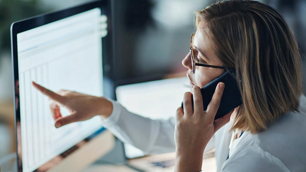 Stock image of a woman on a mobile phone in an office