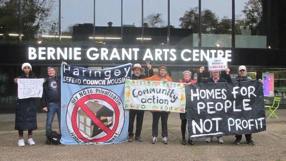 Seven residents holding banners of various colours and sizes, including one saying 'homes for people not profit'