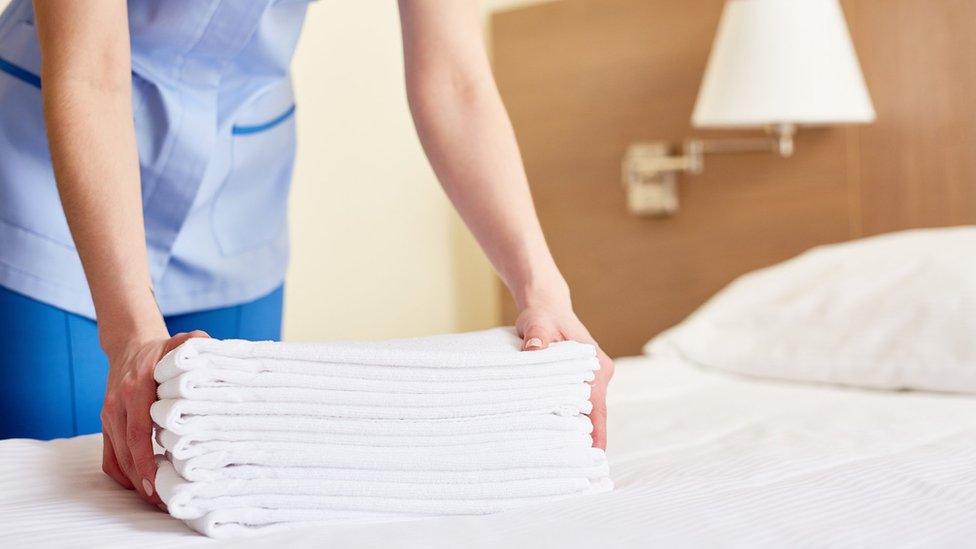 Hotel worker in hotel bedroom