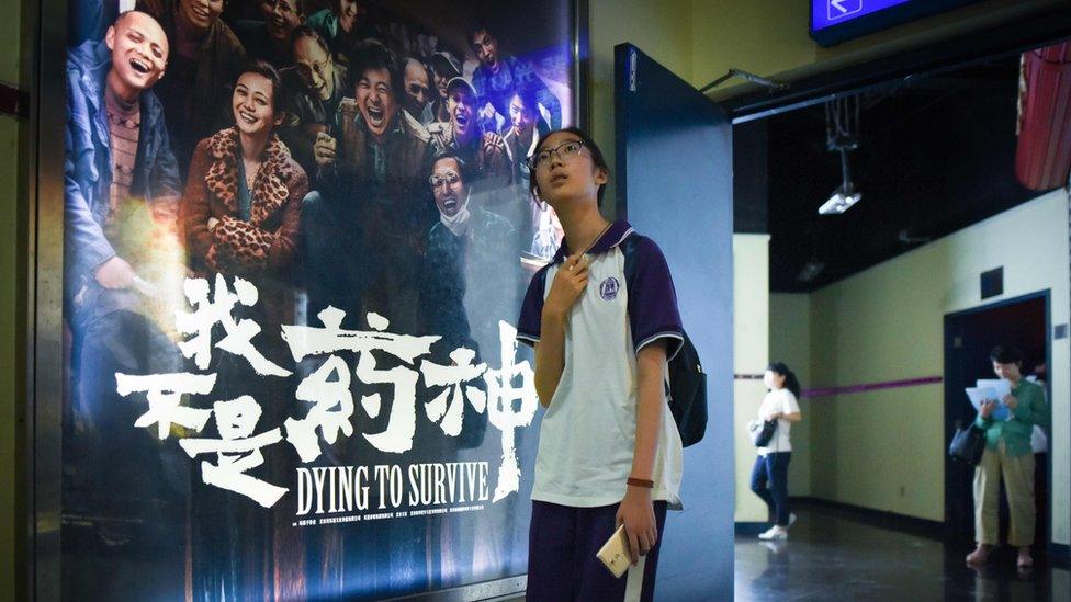 A girl walks past a poster of the film Dying to Survive at a cinema in Beijing, 12 July