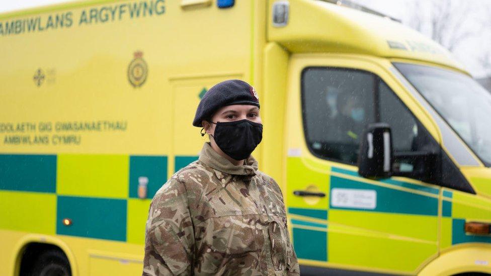 A member of the armed forces in front of a Welsh ambulance