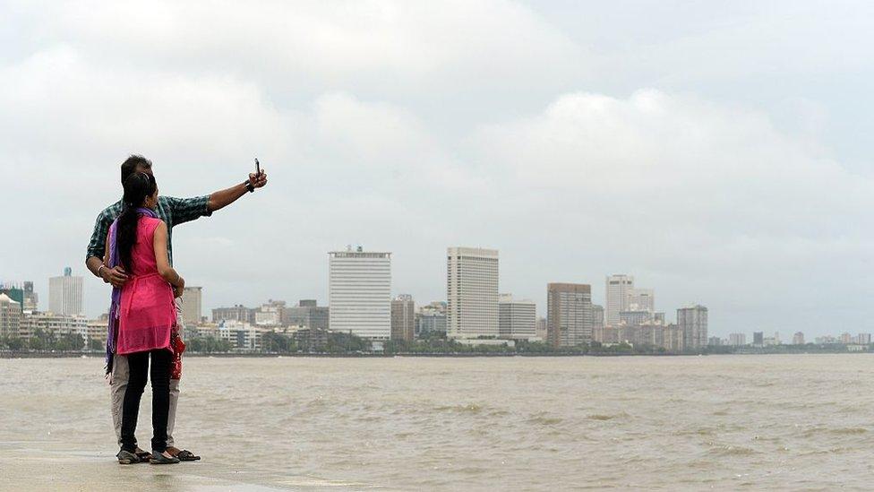 In this photograph taken on June 15, 2015, a young Indian couple take a 'selfie' on Marine Drive promenade in Mumbai.