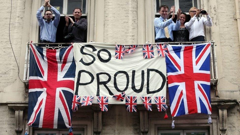 People applaud behind a banner reading - so proud, London, Sept 2012