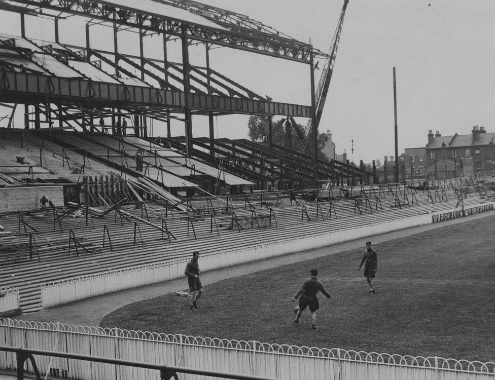 Tottenham Hotspur players Walter Alsford, Michelles and George Greenfield training on the pitch at White Hart Lane in front of where the new East Stand is being built, 26th July 1934