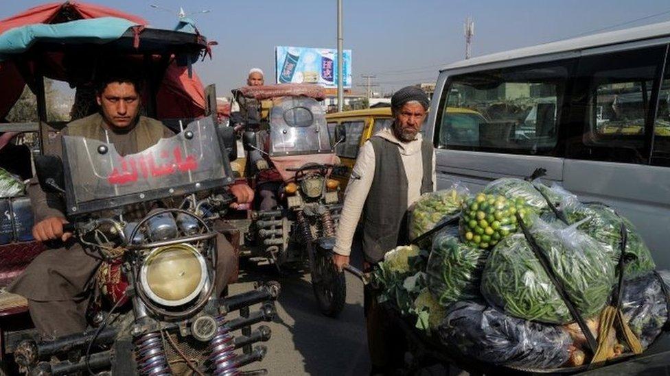 A man pushes wheelbarrow filled with vegetables and fruits at the market in Kabul, Afghanistan