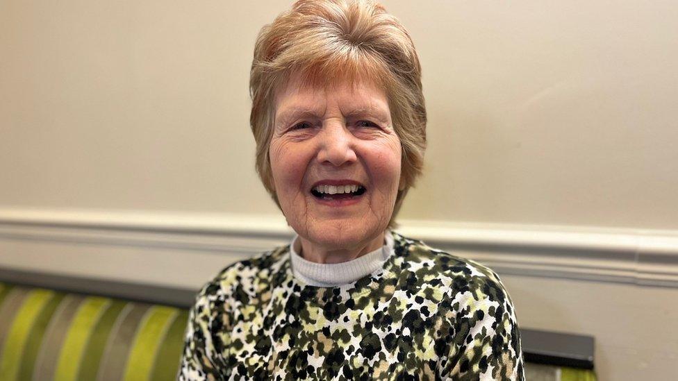 a smiling woman on a green bench