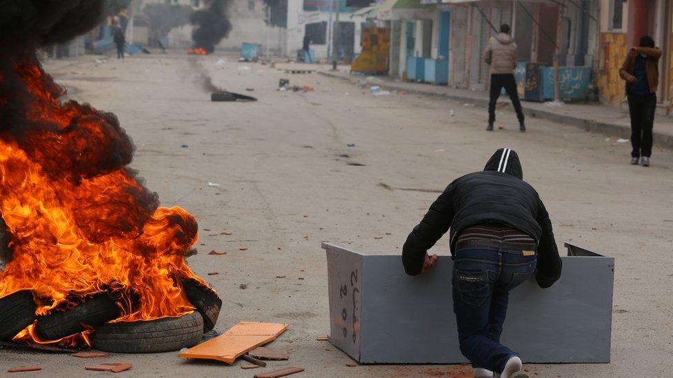 Tunisian boys throw stones towards a police station in a town at the border with Libya