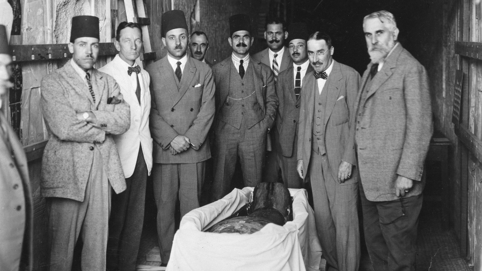 A group of English and Egyptian experts crowded around the mummy of Tutankhamun.
