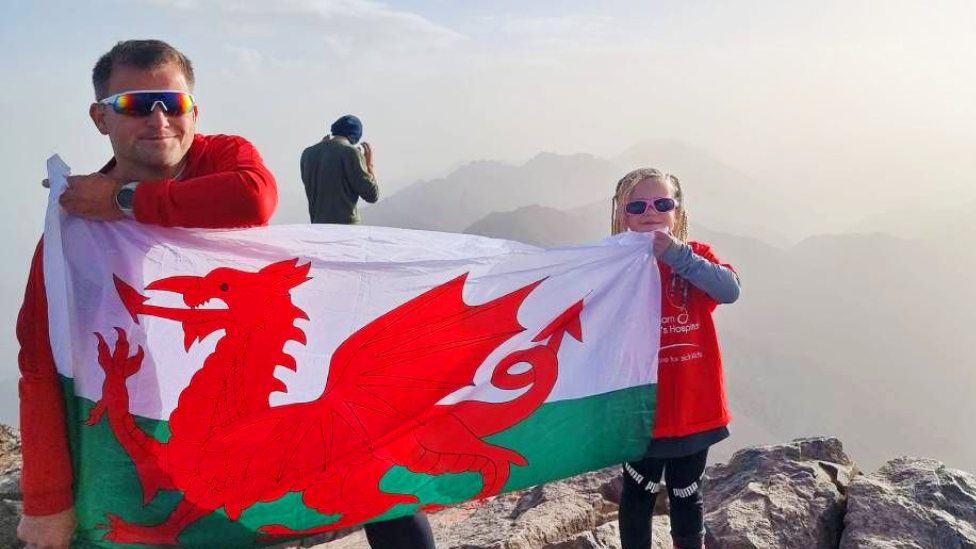 Glyn and Seren Price at the top of Mount Toubkal holding the Welsh flag