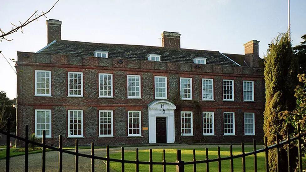 Sussex Police headquarters, a brown brick building surrounded by grass and black gates