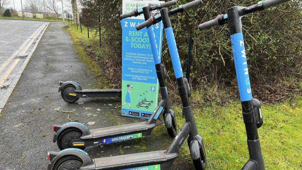 Four blue scooters lined up on a pavement