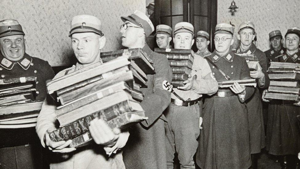 Nazi officials carrying away books, presumably to be burned