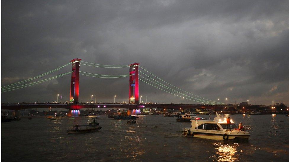 The lights on the Ampera Bridge over the Musi River are turned on during a total solar eclipse in Palembang, South Sumatra