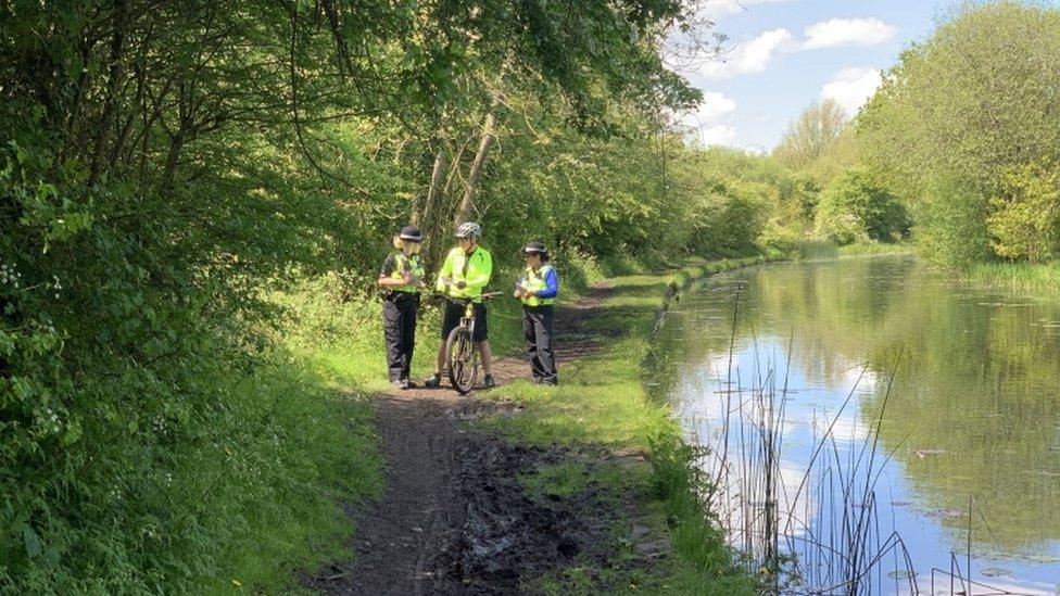 Officers speak to a passer-by about the discovery in Rough Wood Country Park