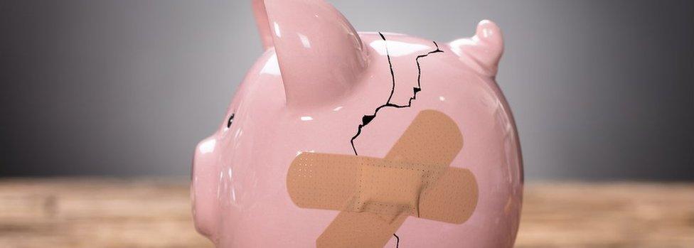 A cracked piggy bank with a plaster across it